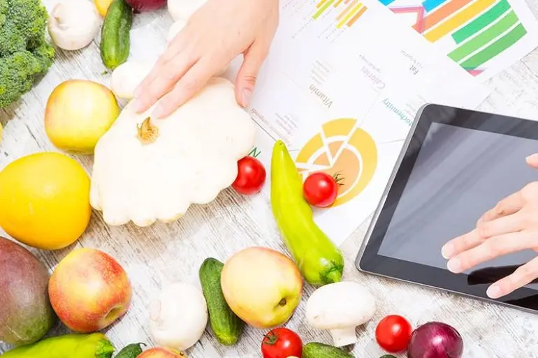 A top view of a variety of vegetables and an a mobile tablet